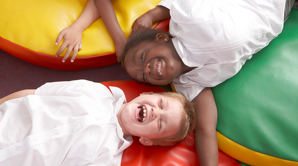 School children lying on colourful beanbags laughing